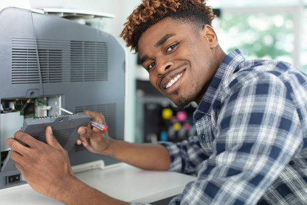 a young man fixing printer - 写真・画像