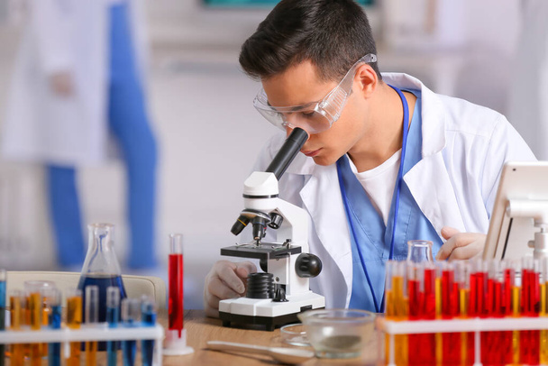 Male scientist working with microscope in laboratory - Photo, image