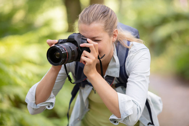 female photographer focusing camera in the countryside - Fotó, kép