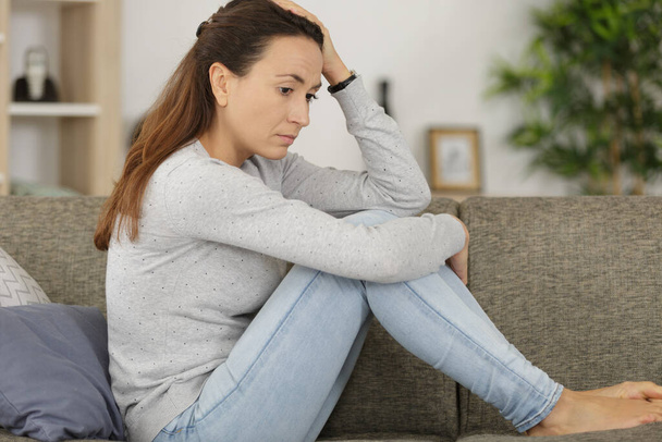 picture of a sad looking woman sitting on the sofa - Photo, Image
