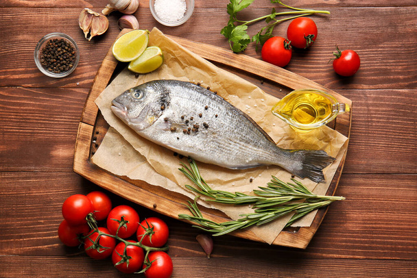 Rauwe dorado vis met ingrediënten op houten ondergrond - Foto, afbeelding