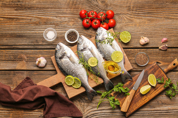 Raw dorado fish with ingredients on wooden background - Zdjęcie, obraz