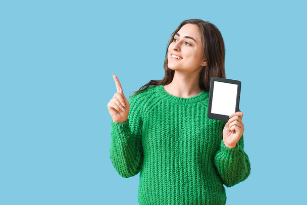 Young woman with e-reader pointing at something on color background - Фото, изображение