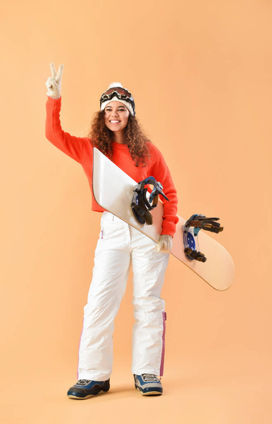 Female snowboarder showing victory gesture on color background - Foto, Imagem