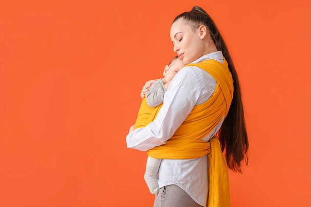 Young mother with little baby in sling on color background - Fotoğraf, Görsel