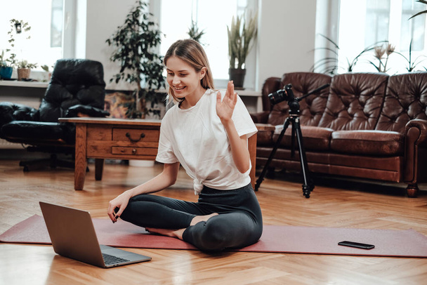 Entrenador de yoga saluda a sus alumnos utilizando un ordenador portátil en la habitación moderna - Foto, Imagen