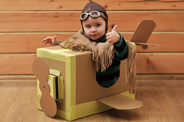 Funny child pilot flying a cardboard box. Child dream. aircraft construction, education. Thumbs up. - Photo, image