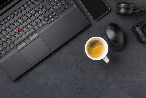 Miejsce pracy i biurko z kawą, laptopem, słuchawkami i smartthpone. Flatlay w kolorze czarnym. - Zdjęcie, obraz