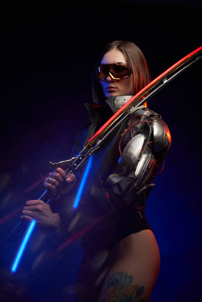 Verführerische Soldatin mit Schwert und kybernetischer Hand im Studio - Foto, Bild