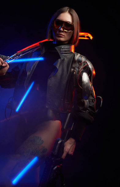 Female mercenary in cyberpunk style going in dark background - Foto, immagini