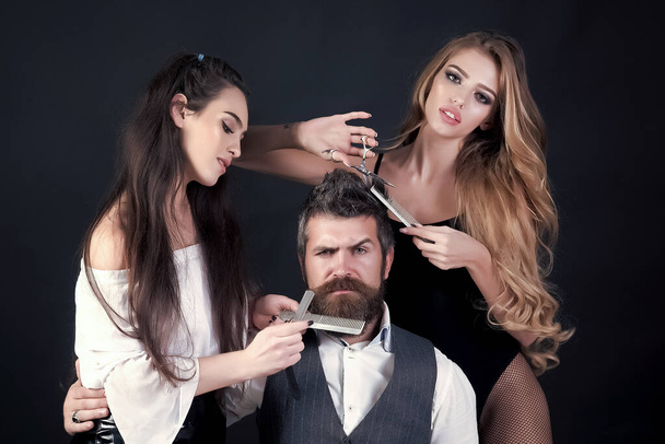 Barbershop concept. Fashion and beauty man, hipster. Sexy girls and brutal bearded hipster with mustache, berd. Barber with straight razor works on haircut. Hipster and sexy girl holds straight razor. - Photo, Image