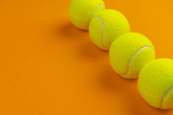 Four tennis balls on an orange background - Φωτογραφία, εικόνα