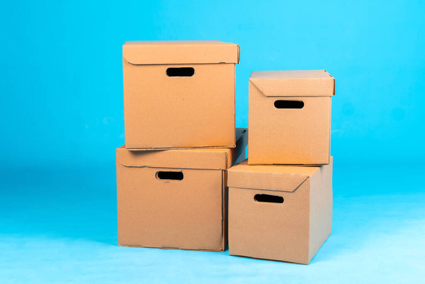 Stack of cardboard boxes on blue background - Фото, зображення