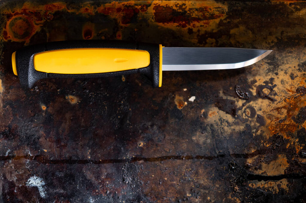 Festes Messermesser vorhanden. Messer mit gelbem Griff vorhanden. Messer auf rostigem Hintergrund. - Foto, Bild