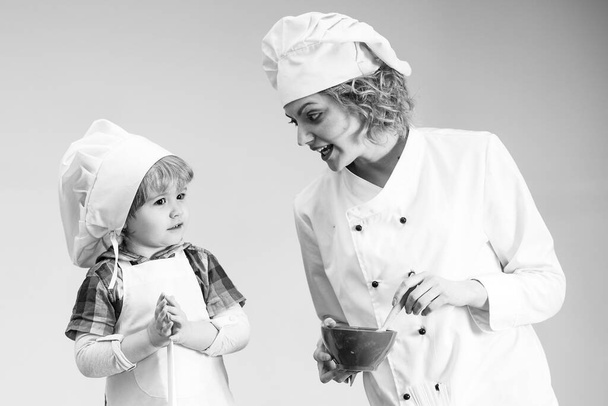 Mother teaches son to cook. Mom and kid with busy face cooking food together. - Fotoğraf, Görsel