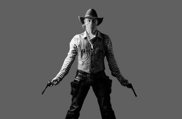 Un uomo con un cappello da cowboy e una pistola. Ovest, armi. Bandito americano mascherato, uomo occidentale con cappello. Ritratto di contadino o cowboy in cappello. Cowboy con un'arma sullo sfondo. Bianco e nero - Foto, immagini