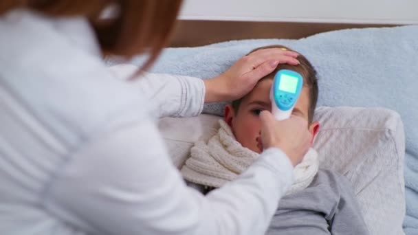 l dziecko z objawami choroby opiekuńczy męski rodzic mierzy wysoką temperaturę w Celsjuszu z bezdotykowym termometrem podczas pandemii spowodowanej koronawirusem - Materiał filmowy, wideo