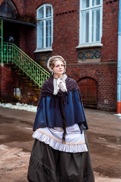 Mulher do século XIX, elegantemente vestida, caminha pelo pátio de um castelo - Foto, Imagem