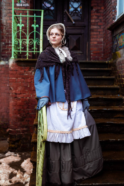 Женщина девятнадцатого века, элегантно одетый, прогуливается по двору замка - Фото, изображение