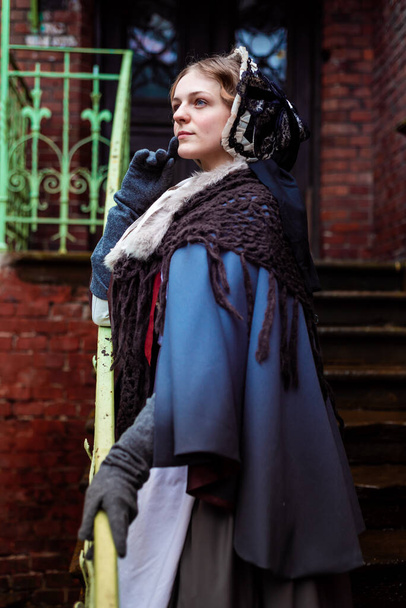 Жінка дев'ятнадцятого століття, елегантно одягнена, проходить через двір замку
 - Фото, зображення