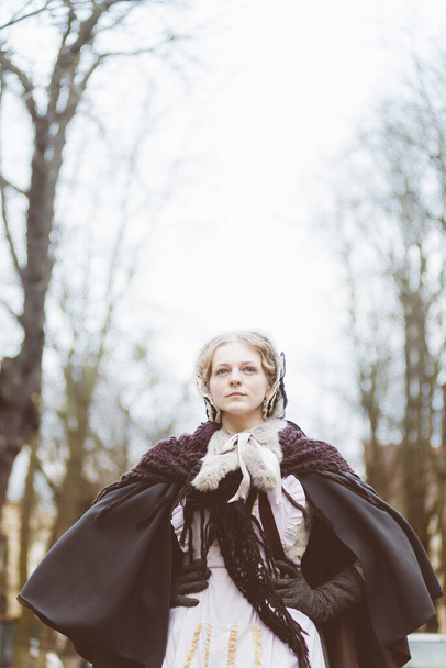 Mujer del siglo XIX, elegantemente vestida, camina por el patio de un castillo - Foto, imagen