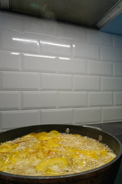 Widok patelni smażącej ziemniaki z cebulą i pieprzem czarnym, w kuchni - Zdjęcie, obraz