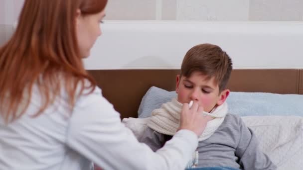 Mutter kümmert sich um die Gesundheit ihrer Söhne und träufelt Nasentropfen von einer Erkältung - Filmmaterial, Video