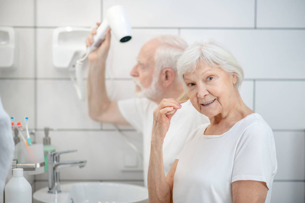 Elderly couple doing hair together in the bathroom - Foto, afbeelding