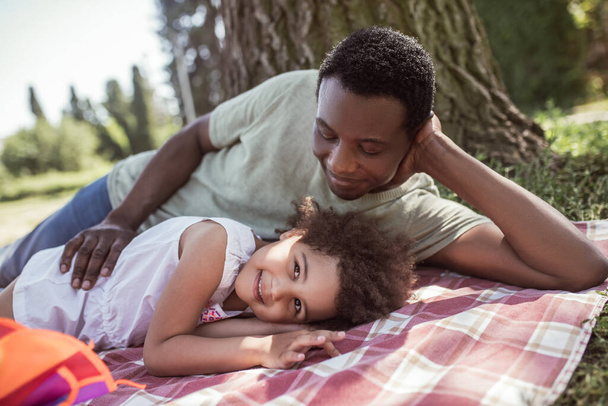 African american man and his cute kid having rest in the park - Fotó, kép