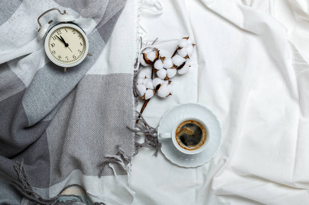 Cozy morning. Breakfast in bed. White and gray bedding, plaid and coffee cup, alarm clock. - Фото, зображення