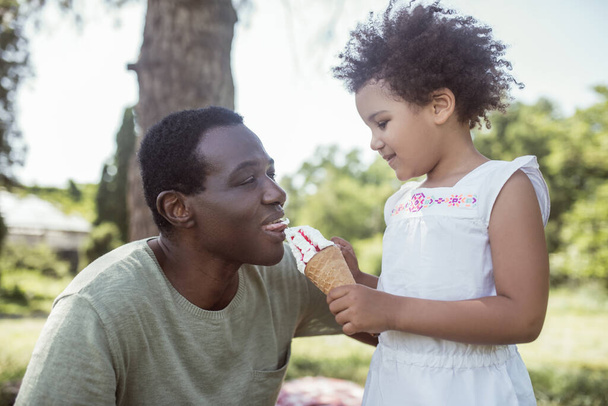 Curly-haired cute kid eating ice-cream and spending time with dad - Photo, Image