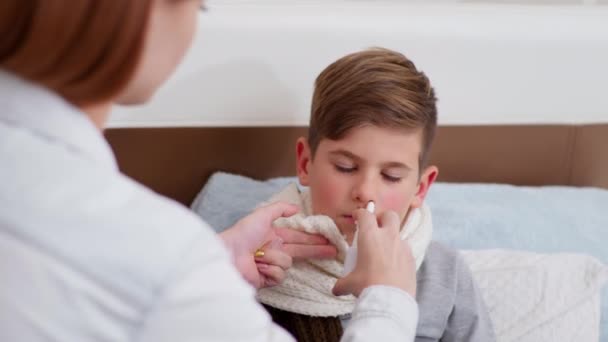 niño con mala salud debido al virus y la infección, el padre femenino gotea gotas en la nariz al hijo enfermo - Metraje, vídeo