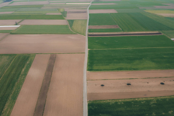 Foto aérea vertical de diferentes campos cubiertos con estiércol o fertilizante. Foto de primavera de campos marrones con fertilizante visible en ellos. - Foto, Imagen