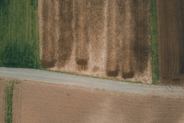 Vertikale Luftaufnahme verschiedener Felder, die mit Gülle oder Dünger bedeckt sind. Frühlingsfoto von braunen Feldern mit sichtbarem Dünger. - Foto, Bild