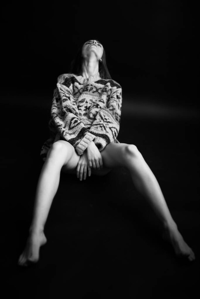 brunette girl with voluminous sweater moves freely and dances, art portrait of a dancer on a black background - Foto, Imagem
