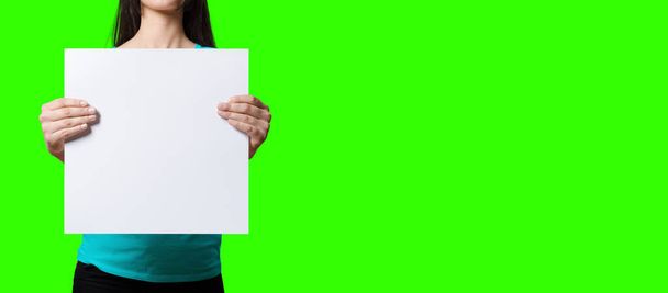 Piękna kobieta trzyma pusty znak na zielonym tle ekranu. dopasuj swój projekt elementu. dodano miejsce na tekst. - Zdjęcie, obraz
