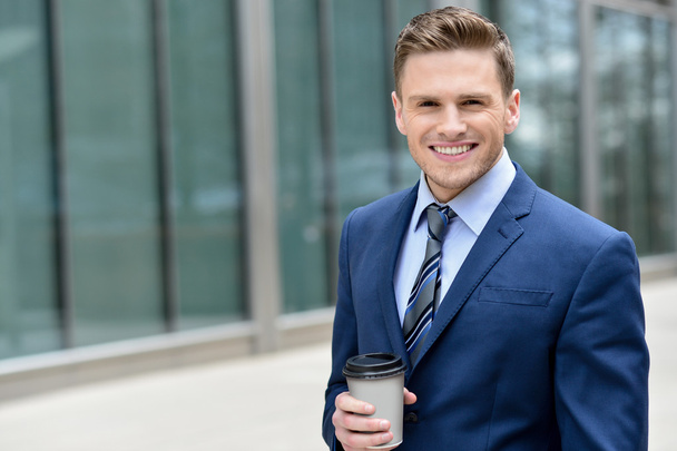 Smiling businessman with coffee sipper - Foto, imagen