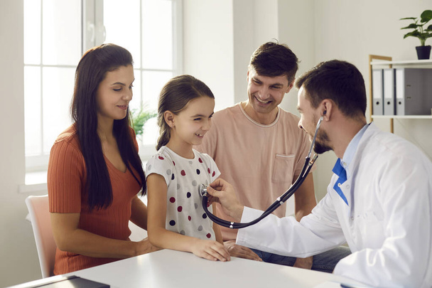 Male doctor puts a stethoscope to the little girls chest and listens to the heartbeat and lungs. - Φωτογραφία, εικόνα