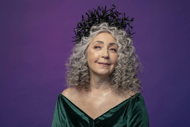 Stúdió portré egy 60-65 éves idős nőről, gyönyörű ruhában, koronával a fején, színes háttérrel. Koncepció: stílusos nyugdíjasok modell megjelenés, aktív élet. - Fotó, kép