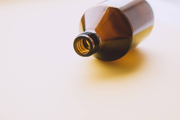 Frasco de vidrio de medicina marrón vacío de líquido cosmético sobre fondo claro. Concepto de la cosmética orgánica, cero residuos - Foto, imagen