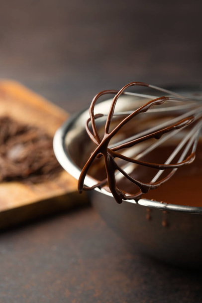 Hausgemachte leckere Schokoladencreme in Schüssel mit Schneebesen auf dunklem Holzhintergrund. Selektiver Fokus, Kopierraum. Super-Brain-Food-Konzept. - Foto, Bild