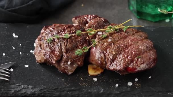 primo piano di carne di manzo alla griglia con spezie sul piatto di pietra nera, zoom dall'alto - Filmati, video