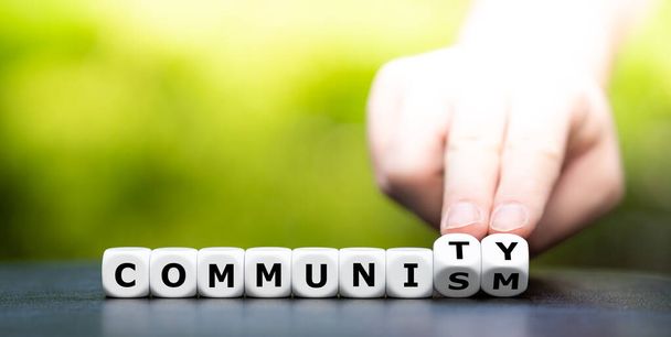 Hand draait dobbelstenen en verandert het woord communisme in gemeenschap. - Foto, afbeelding