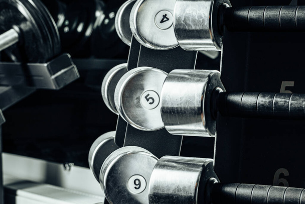 Sports equipment in gym. Dumbbells of different weight close up - Foto, Bild