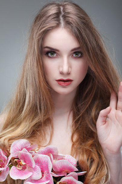 Beautiful  girl, isolated on a light - grey  background with pink orchids , emotions, cosmetics - Foto, immagini