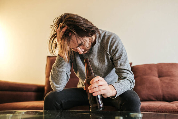  Alcohol addiction at young age. Caucasian male cannot stop drinking alcohol, male with bottle of beer. Loneliness, depression and alcoholism  - Fotó, kép