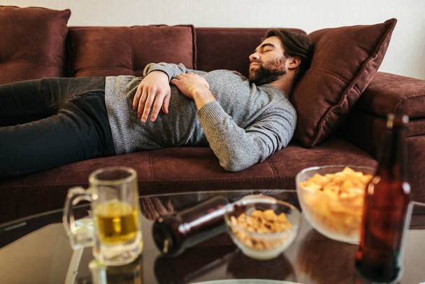 guy sleeps on the sofa in the living room after a new year's party, Christmas and New Year celebrations. sleeping male drunk after a party. - 写真・画像