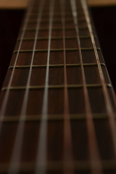 гітарна шия з фризами та металевими струнами на темному фоні
 - Фото, зображення