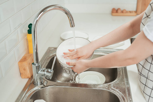 Женщина моет посуду на современной кухне, крупным планом - Фото, изображение