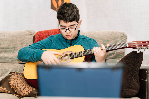 giovane adolescente imparare a suonare la chitarra classica spagnola con un tablet attraverso Internet dalla distanza sociale di covid-19 - Foto, immagini